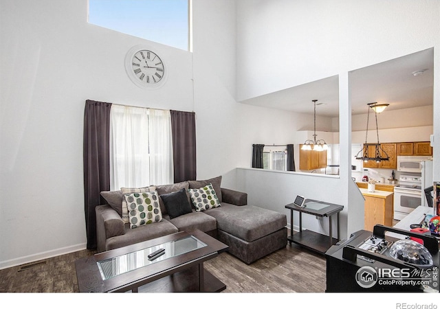 living room with a high ceiling, hardwood / wood-style flooring, plenty of natural light, and a chandelier