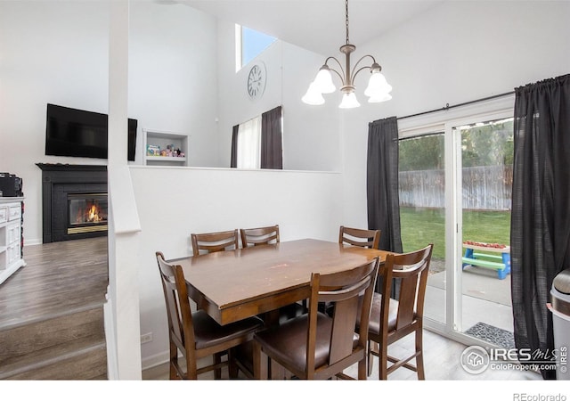 dining room with an inviting chandelier, hardwood / wood-style flooring, a high ceiling, and a tile fireplace