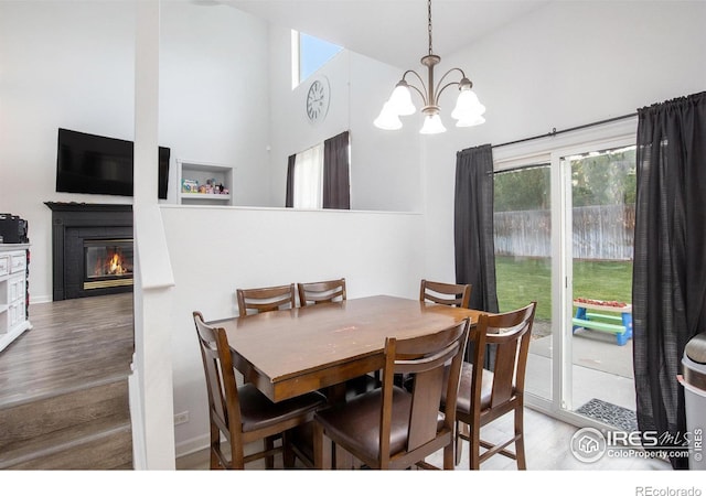 dining space featuring a healthy amount of sunlight, an inviting chandelier, a glass covered fireplace, and wood finished floors