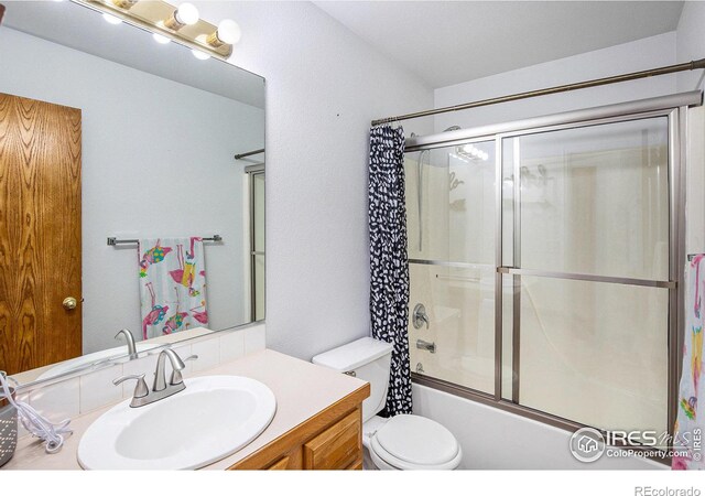 full bathroom with enclosed tub / shower combo, vanity, and toilet