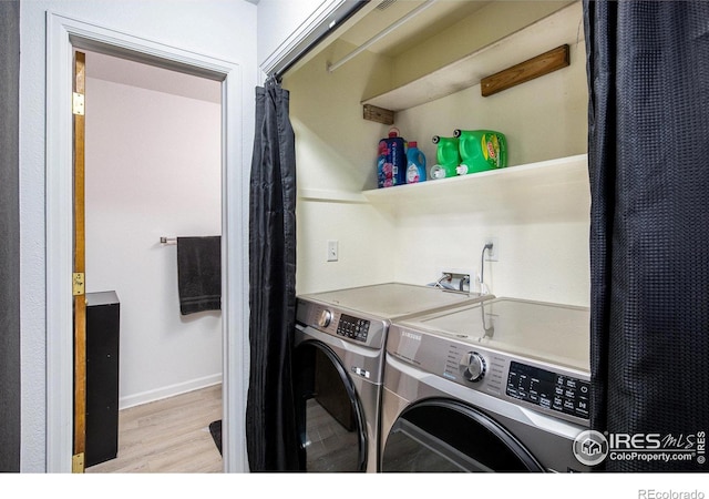 washroom featuring baseboards, light wood finished floors, separate washer and dryer, and laundry area