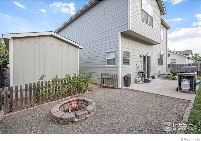 rear view of house featuring a patio, fence, an outdoor fire pit, and an outbuilding