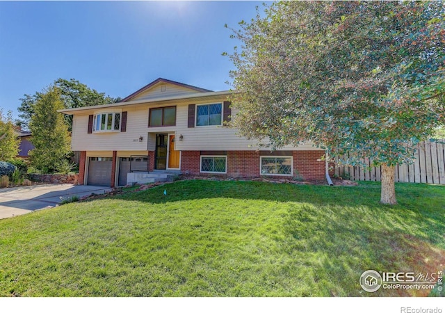 raised ranch featuring a garage and a front lawn