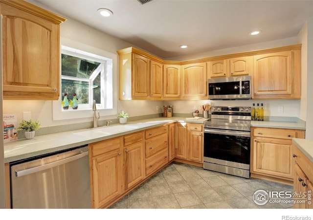 kitchen with light tile patterned floors, light brown cabinets, stainless steel appliances, and sink