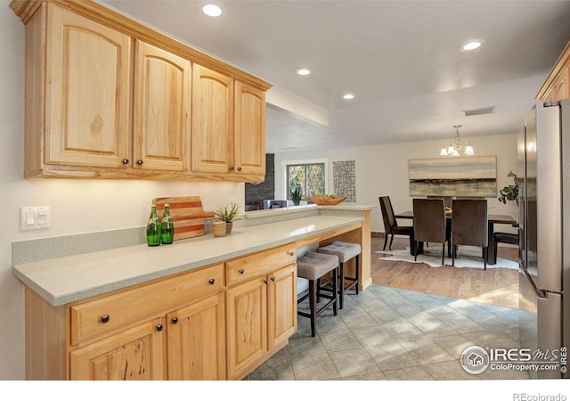 kitchen with pendant lighting, light hardwood / wood-style floors, light brown cabinets, and an inviting chandelier