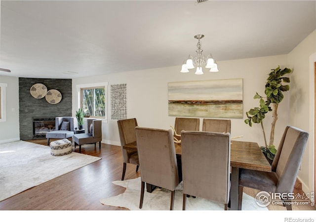 dining space with hardwood / wood-style flooring, a chandelier, and a large fireplace