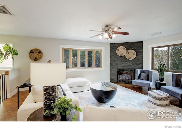 living room with a large fireplace, hardwood / wood-style flooring, and ceiling fan