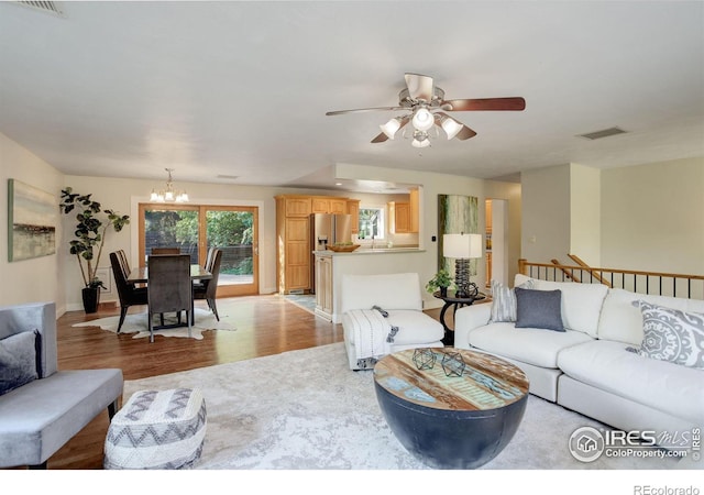 living room with ceiling fan with notable chandelier and light hardwood / wood-style flooring