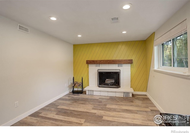 living room with a fireplace, wooden walls, and wood-type flooring