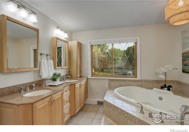 bathroom with tiled tub, tile patterned flooring, and vanity