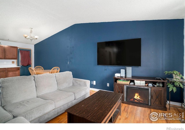 1900 Logan St, Longmont, CO 80501 - living area featuring an inviting chandelier, wood finished floors, a lit fireplace, and vaulted ceiling