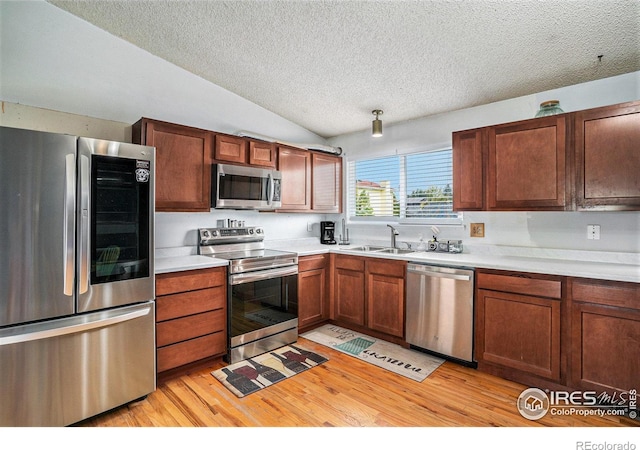 1900 Logan St, Longmont, CO 80501 - kitchen with a textured ceiling, a sink, vaulted ceiling, stainless steel appliances, and light wood-type flooring