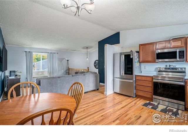 1900 Logan St, Longmont, CO 80501 - kitchen featuring lofted ceiling, brown cabinetry, a chandelier, light wood-style floors, and stainless steel appliances
