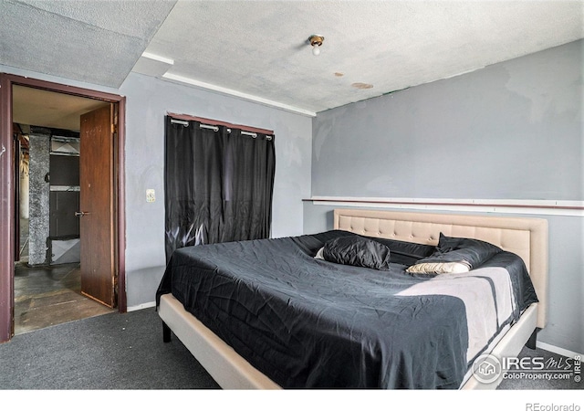 bedroom featuring dark carpet and a textured ceiling