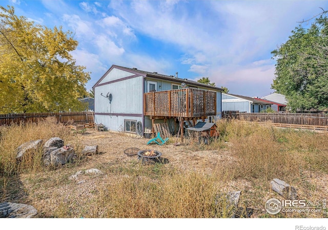 back of house with a fire pit and a wooden deck