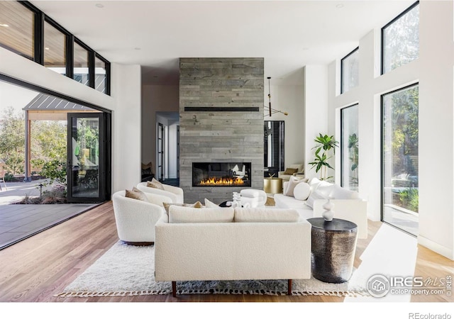 living room with a towering ceiling, light hardwood / wood-style floors, and a tile fireplace