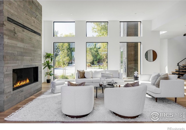 living room with wood-type flooring, a high ceiling, and a large fireplace