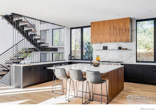 kitchen with a kitchen island, light wood-type flooring, tasteful backsplash, a wall of windows, and a kitchen breakfast bar