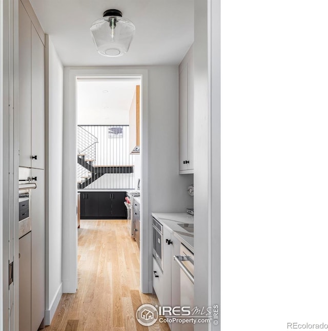 kitchen featuring white cabinetry, stainless steel dishwasher, and light hardwood / wood-style flooring