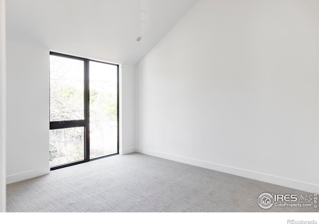 carpeted spare room with vaulted ceiling