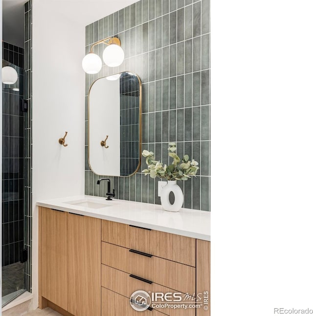 bathroom with a shower with door, vanity, and backsplash