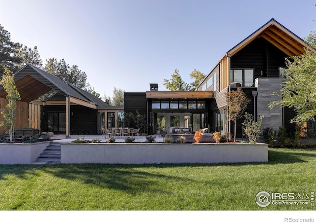 rear view of property featuring a balcony, a yard, and a patio area