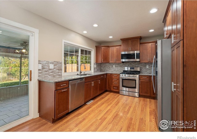 kitchen featuring light stone counters, sink, tasteful backsplash, appliances with stainless steel finishes, and light hardwood / wood-style floors