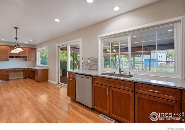 kitchen featuring dishwasher, light hardwood / wood-style floors, light stone counters, and sink