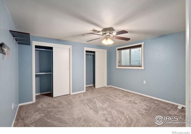 unfurnished bedroom with carpet floors, two closets, and ceiling fan