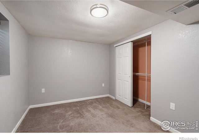 unfurnished bedroom featuring a textured ceiling, a closet, and carpet flooring