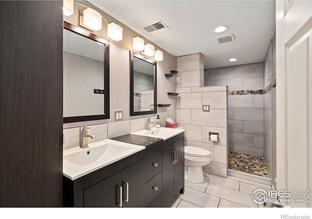 bathroom featuring tile patterned flooring, toilet, vanity, tile walls, and tiled shower