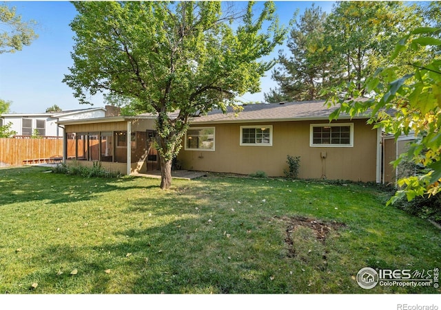 back of property featuring a sunroom and a lawn