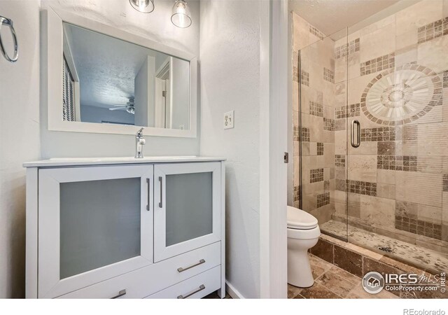 bathroom featuring vanity, toilet, a textured ceiling, and a shower with shower door