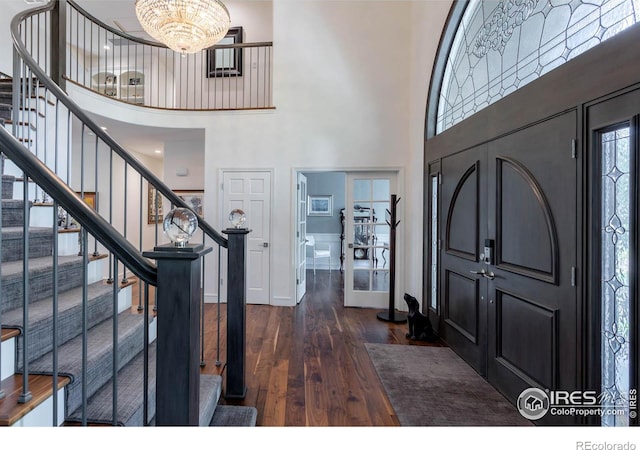 foyer featuring dark wood-type flooring, a high ceiling, and an inviting chandelier