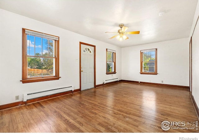 interior space with hardwood / wood-style floors, ceiling fan, a wealth of natural light, and a baseboard heating unit