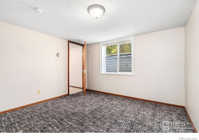 spare room with dark colored carpet and a textured ceiling