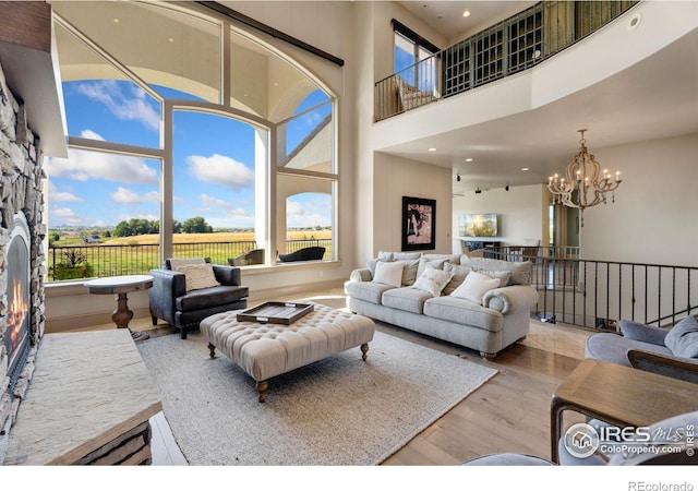 living room with a high ceiling, a notable chandelier, and light hardwood / wood-style floors