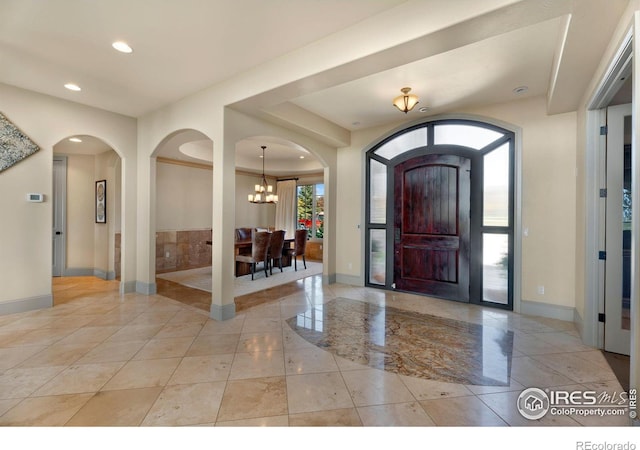 foyer featuring recessed lighting, baseboards, a chandelier, and arched walkways