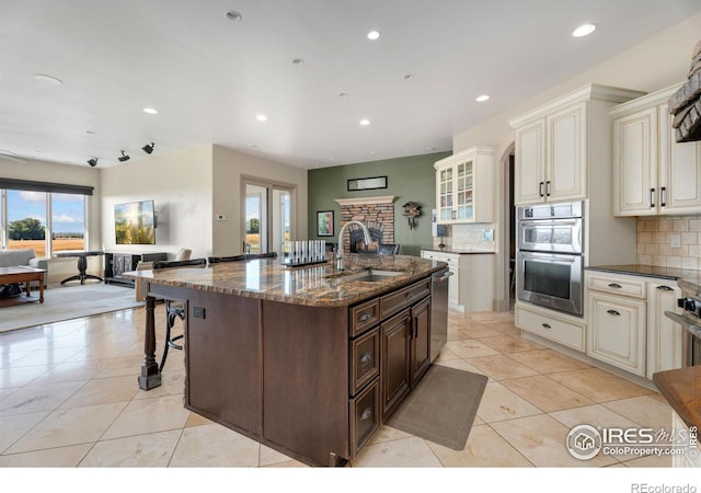 kitchen featuring a sink, stainless steel appliances, recessed lighting, tasteful backsplash, and dark stone counters