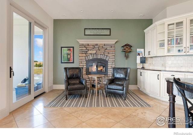 living area with light tile patterned floors, a stone fireplace, recessed lighting, and baseboards
