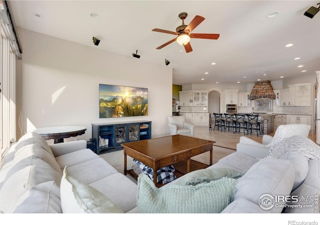 living room featuring a ceiling fan, recessed lighting, and arched walkways