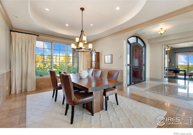 dining area with ceiling fan with notable chandelier, crown molding, and a tray ceiling