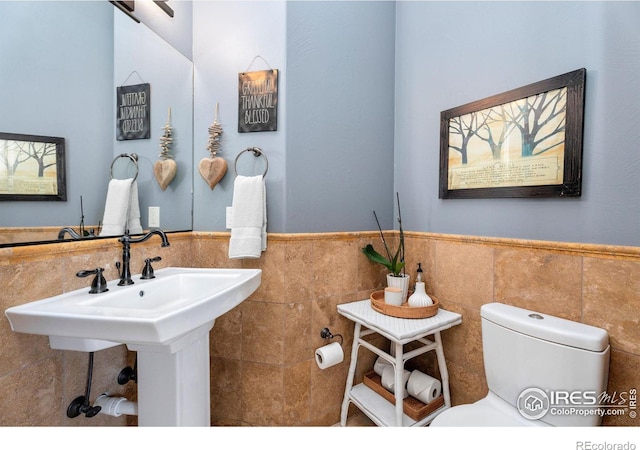 bathroom with tile walls and toilet