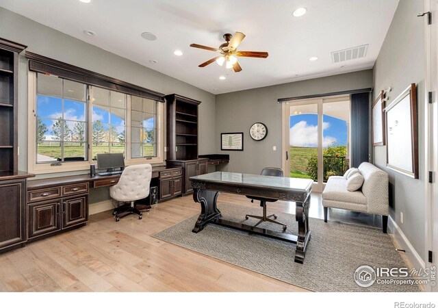 home office featuring light wood-type flooring, ceiling fan, and built in desk