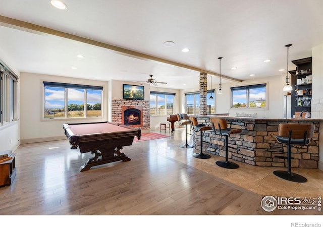 recreation room featuring pool table, a stone fireplace, a ceiling fan, wood finished floors, and bar with sink