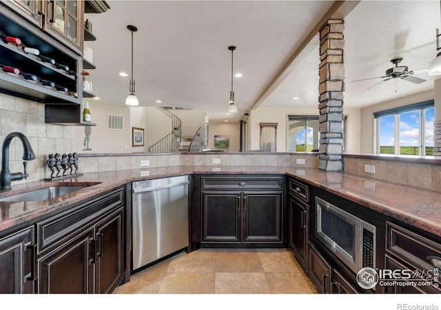 kitchen featuring appliances with stainless steel finishes, a sink, backsplash, dark stone countertops, and pendant lighting