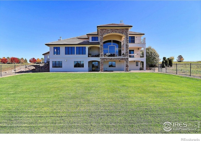 rear view of property featuring a balcony and a yard