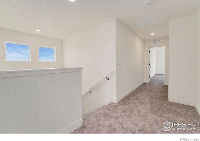 hallway featuring visible vents, carpet floors, baseboards, recessed lighting, and an upstairs landing