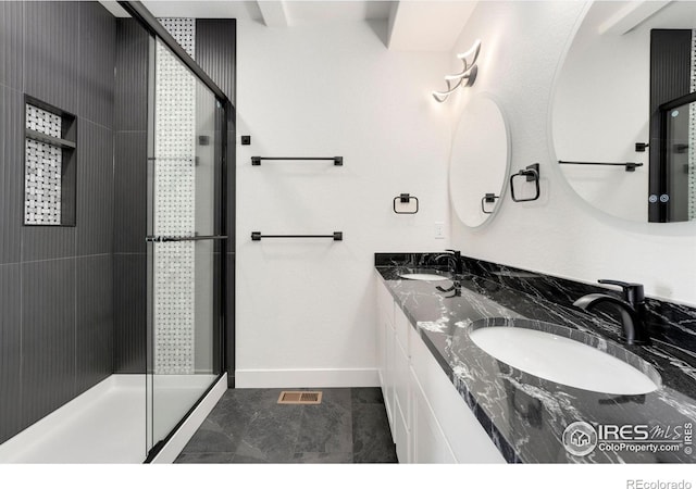 bathroom featuring a stall shower, baseboards, visible vents, and a sink