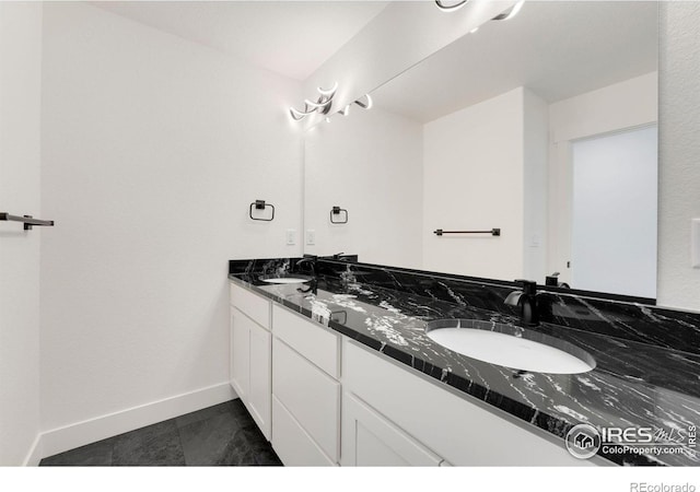 bathroom with double vanity, baseboards, and a sink